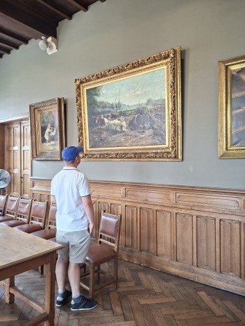 Een man bekijkt schilderijen in het stadhuis van Dendermonde